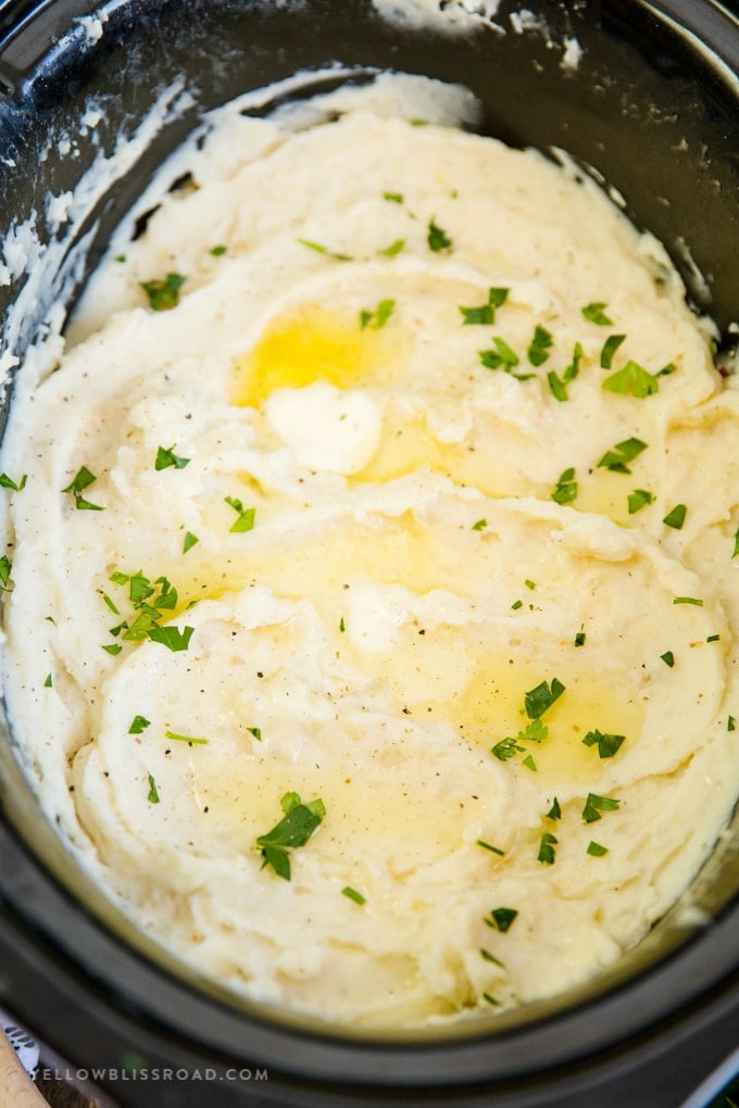 Slow Cooker Mashed Potatoes with melted butter and parsley on top.