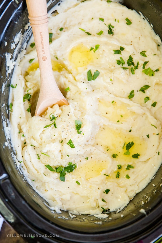 Crock Pot Mashed Potatoes are so easy, creamy & delicious. With just 5 ingredients, these slow cooker mashed potatoes will make cooking Thanksgiving Dinner a breeze! Slow Cooker Mashed Potatoes with a wooden spoon | Crock Pot Mashed Potatoes