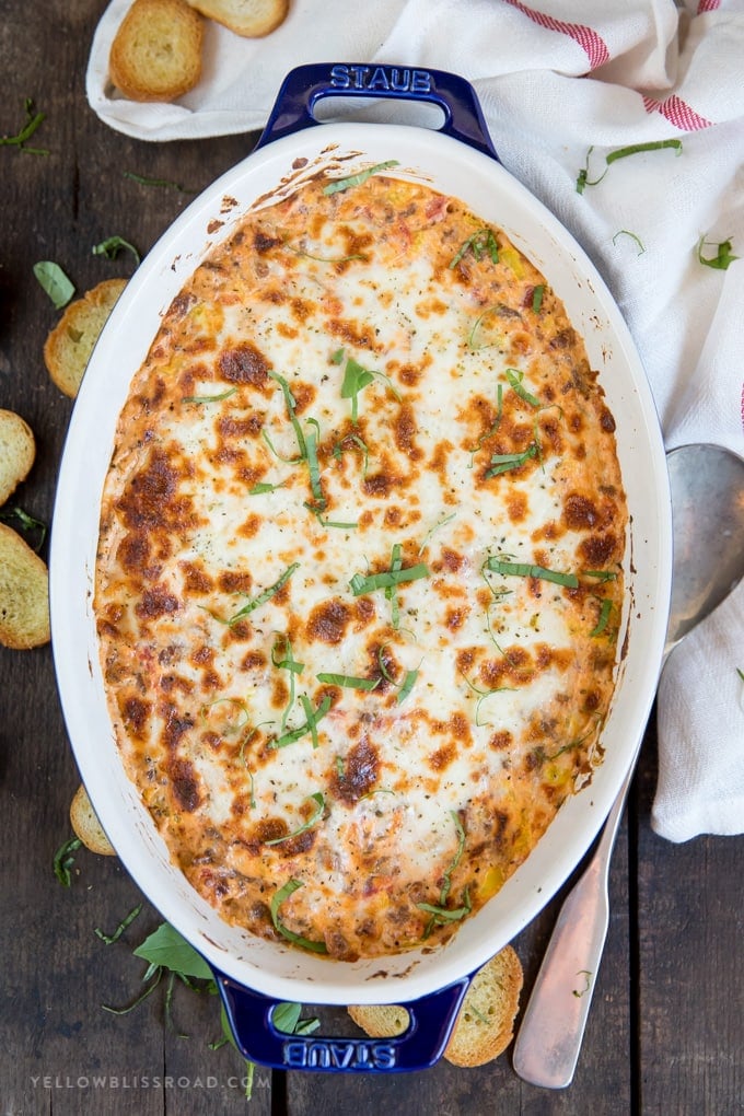 Spicy Italian Sausage Dip in a large casserole baking dish surrounded by toasted bread.