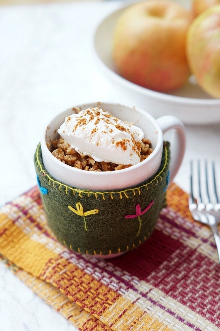 microwave apple crisp in a mug with whipped cream on top