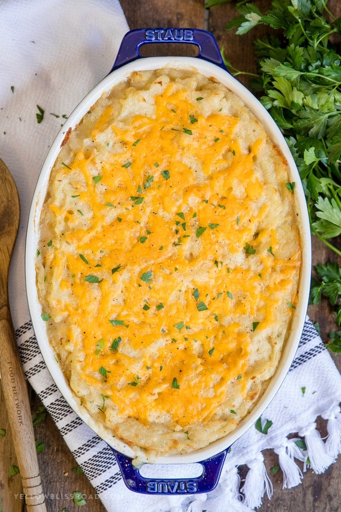 An overhead shot of a turkey shepherd's pie in a casserole dish with parsley and a wooden spoon. 