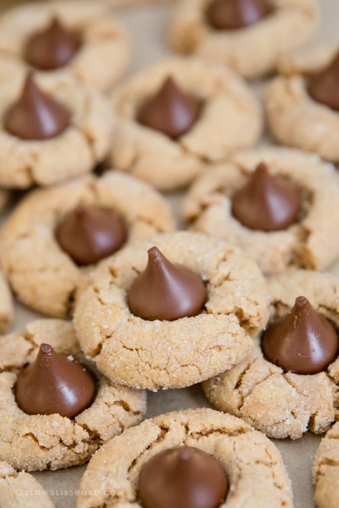 Close up of a peanut butter blossom cookie on parchment paper.