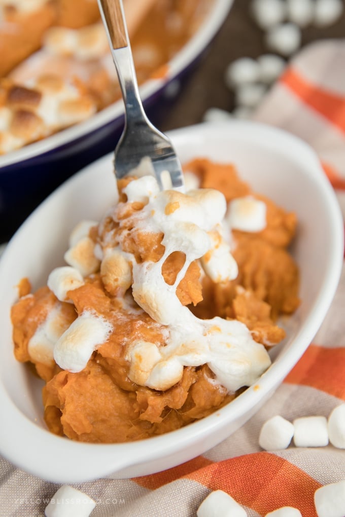 My Sweet Potato Casserole Recipe is a classic Thanksgiving side dish with fresh mashed sweet potatoes, brown sugar, cinnamon, and topped with marshmallows! Sweet potato Casserole in a small dish with a serving on a fork.
