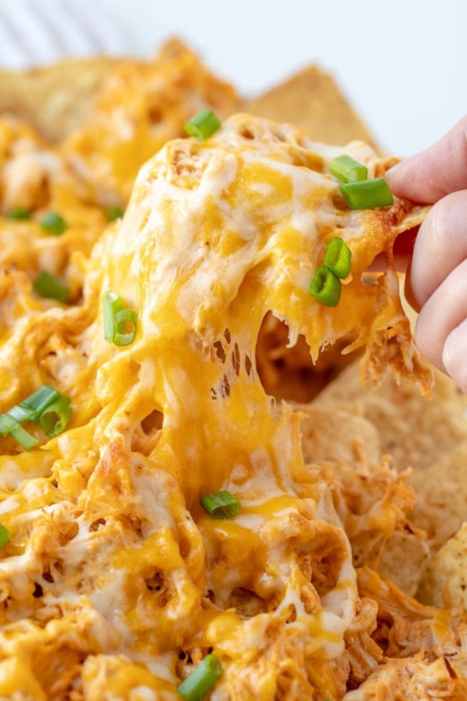 Buffalo chicken nachos with a hand pulling them apart.