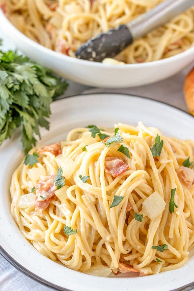 A plate of pasta carbonara with bacon and parsley.