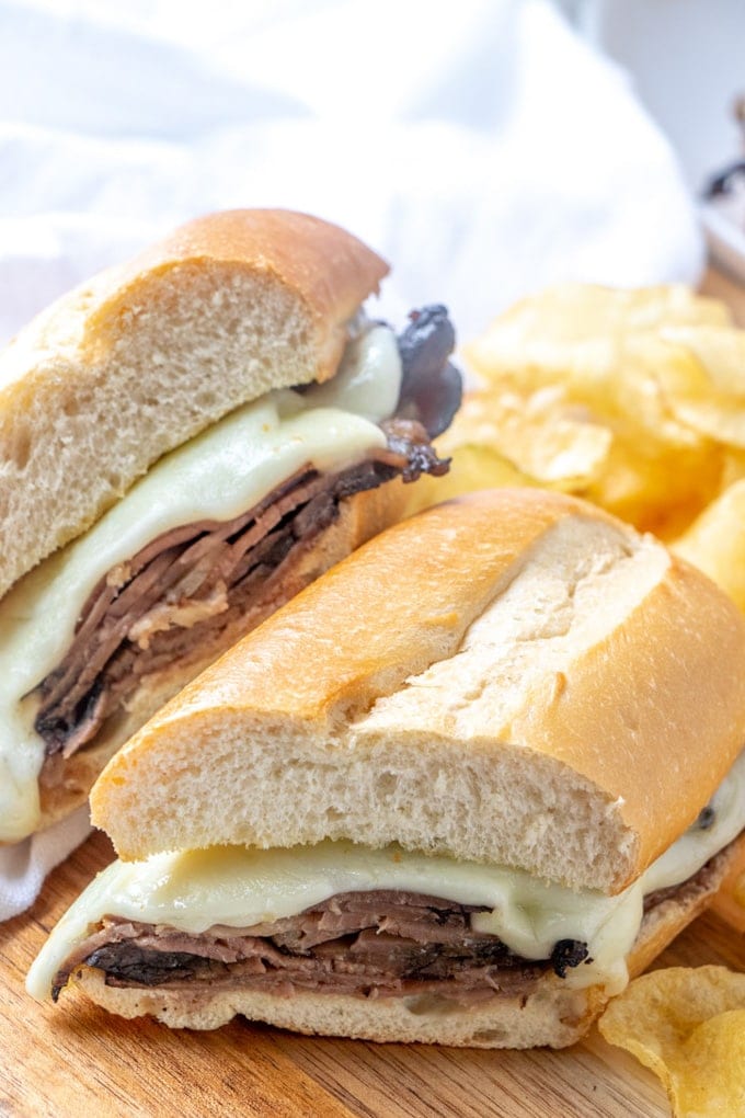 Two halves of a French Dip Sandwich with potato chips.