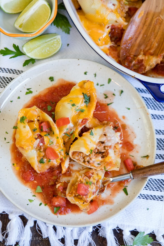 Ground Turkey Taco Stuffed Shells on a plate with a fork and limes.