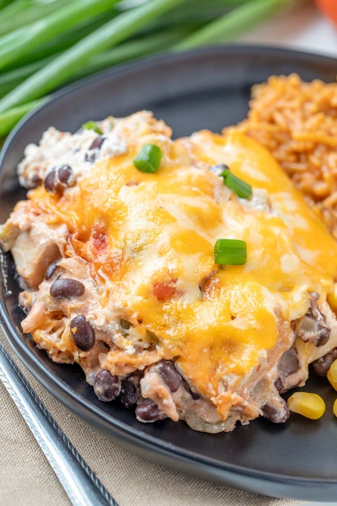 mexican chicken casserole with beans and cheese on a plate next to rice