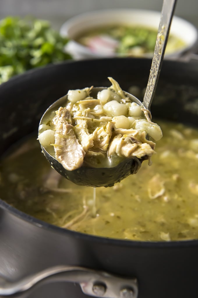 Ladle of Pozole Verde soup with chicken and hominy