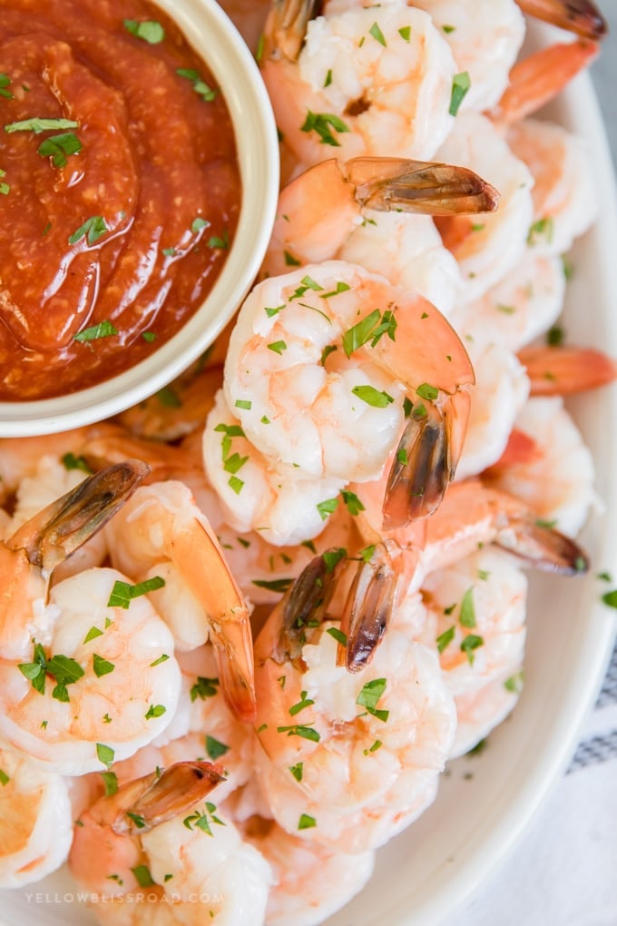 Shrimp Cocktail is a classic appetizer of flavorful, poached shrimp served with a homemade cocktail sauce that is party ready in less than 20 minutes. A large platter of shrimp cocktail with cocktail sauce for dipping.