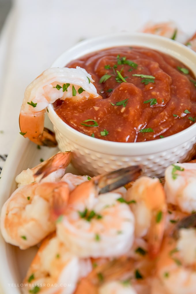 A shrimp dipped in a bowl of cocktail sauce.