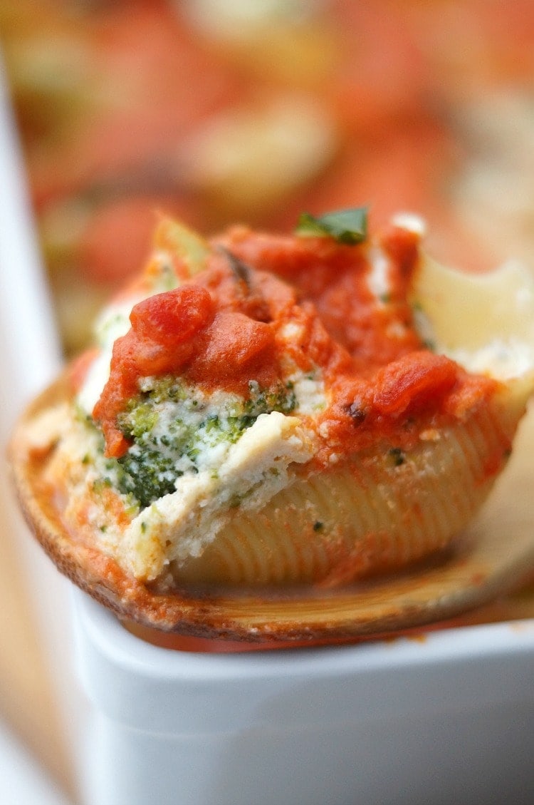 close up of spoon lifting stuffed shell out of baking dish