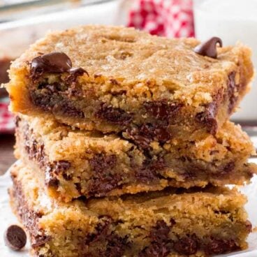 A stack of chocolate chip cookie bars with a glass of milk.