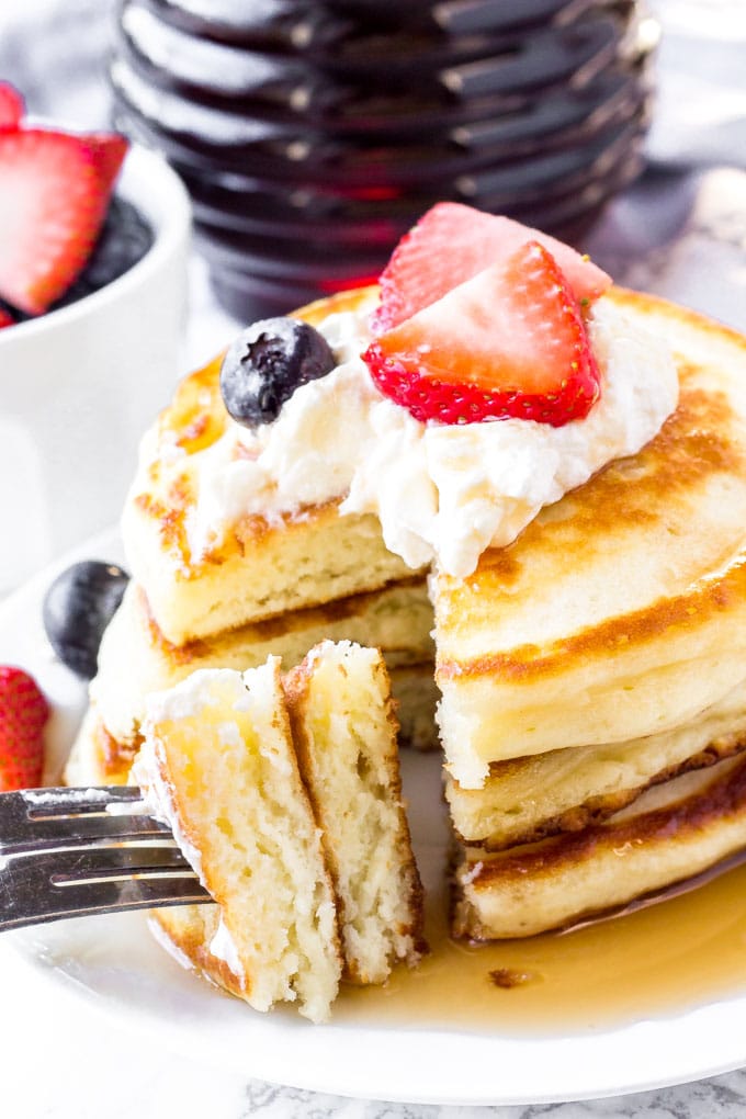 A stack of homemade pancakes with a bite taken out of it. 