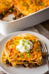 slice of mexican lasagna on a plate garnished with sour cream and green onion