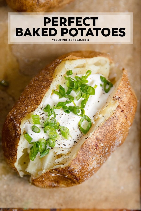A close up of a baked potato with sour cream and chives on top