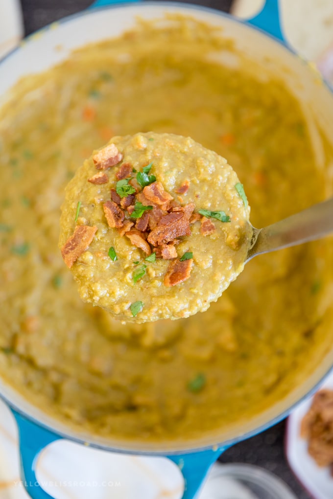 This Split Pea Soup Recipe with Bacon has a thick and creamy, split pea base, loaded with veggies, seasonings and tons of crunchy, salty bacon. A ladle full of split pea soup with bacon hovering over the pot.