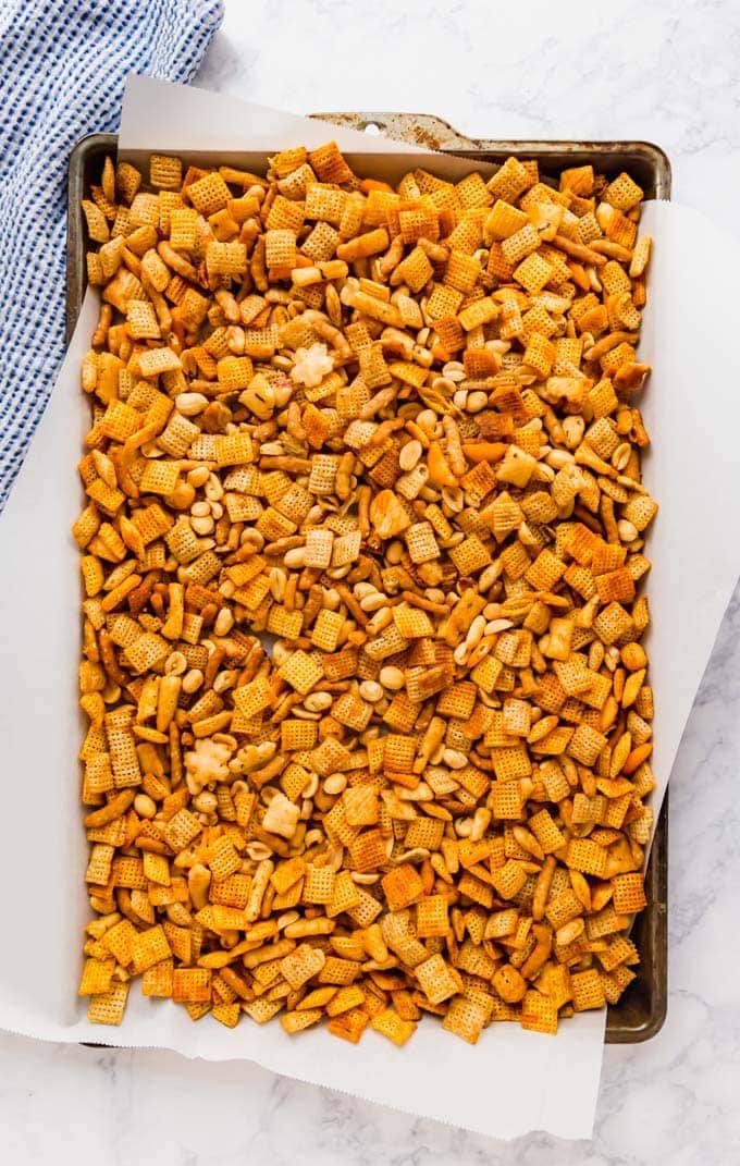 An overhead image of Sriracha Chex Mix on a baking sheet with parchment paper.