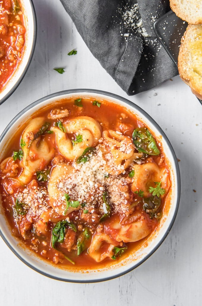 An overhead shot of tomato tortellini soup with sausage