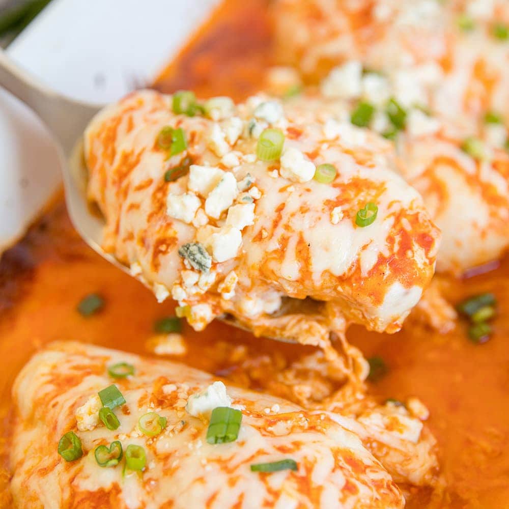 buffalo chicken breasts in a baking dish with a spatula.