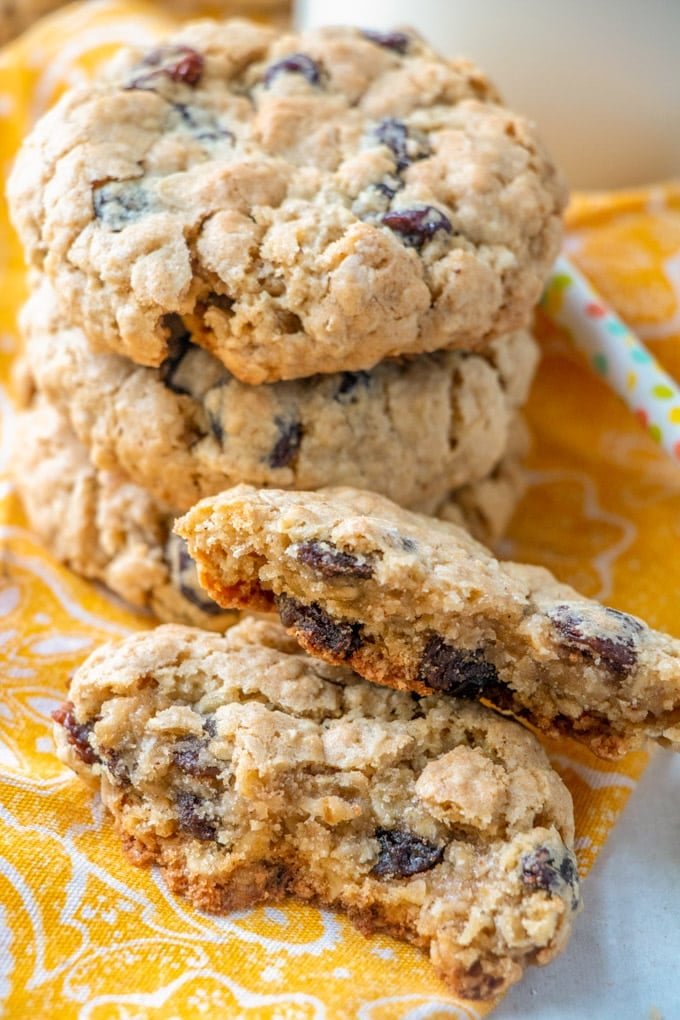 A stack of oatmeal cookies, with one broken in half on a yellow bapkin