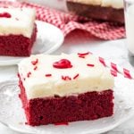 Red velvet brownie with cream cheese frosting on a white plate.