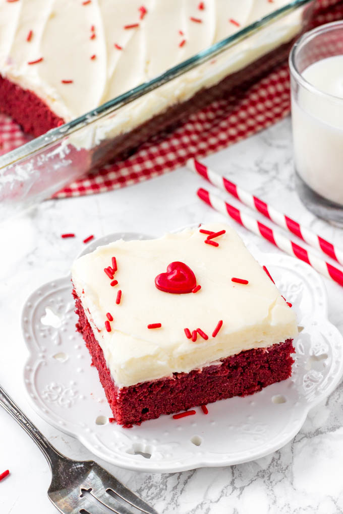 Overhead shot of a red velvet brownie with cream cheese frosting and red sprinkles on top. 