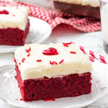 Red velvet brownie with cream cheese frosting on a white plate.