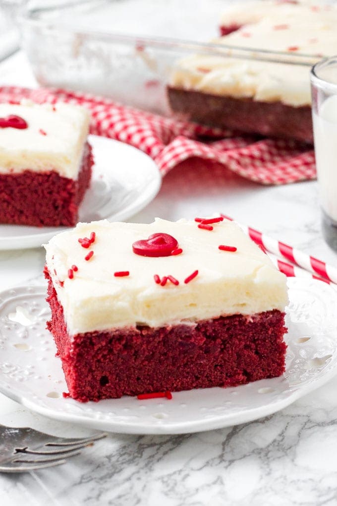 Red velvet brownie with cream cheese frosting on a white plate. 