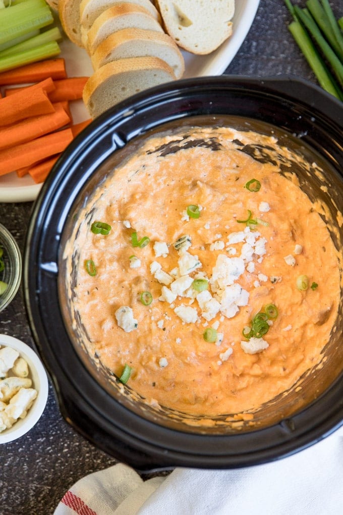 Buffalo Chicken Dip in a crock pot surrounded by carrots, celery and bread.
