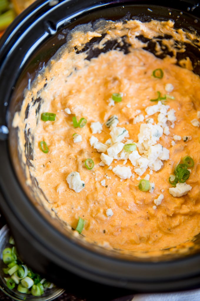Slow cooker buffalo chicken dip with blue cheese crumbles and green onions.