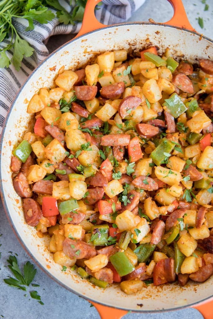 An overhead shot of smoked sausage and potato hash in a large skillet.