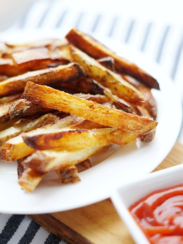 Close up of a plate of baked homemade french fries.