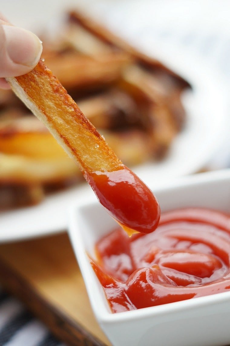 A crispy oven baked french fry dipped in ketchup.