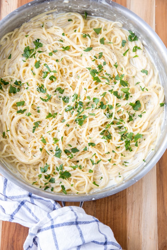 This Four Cheese Spaghetti is ultra creamy and garlicky. It comes together in under 20 minutes, making it a perfect weeknight meal. An overhead shot of a pan of four cheese spaghetti