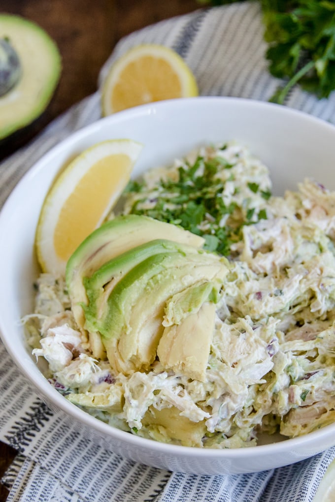 Avocado Chicken salad close up image with sliced avocados and lemon