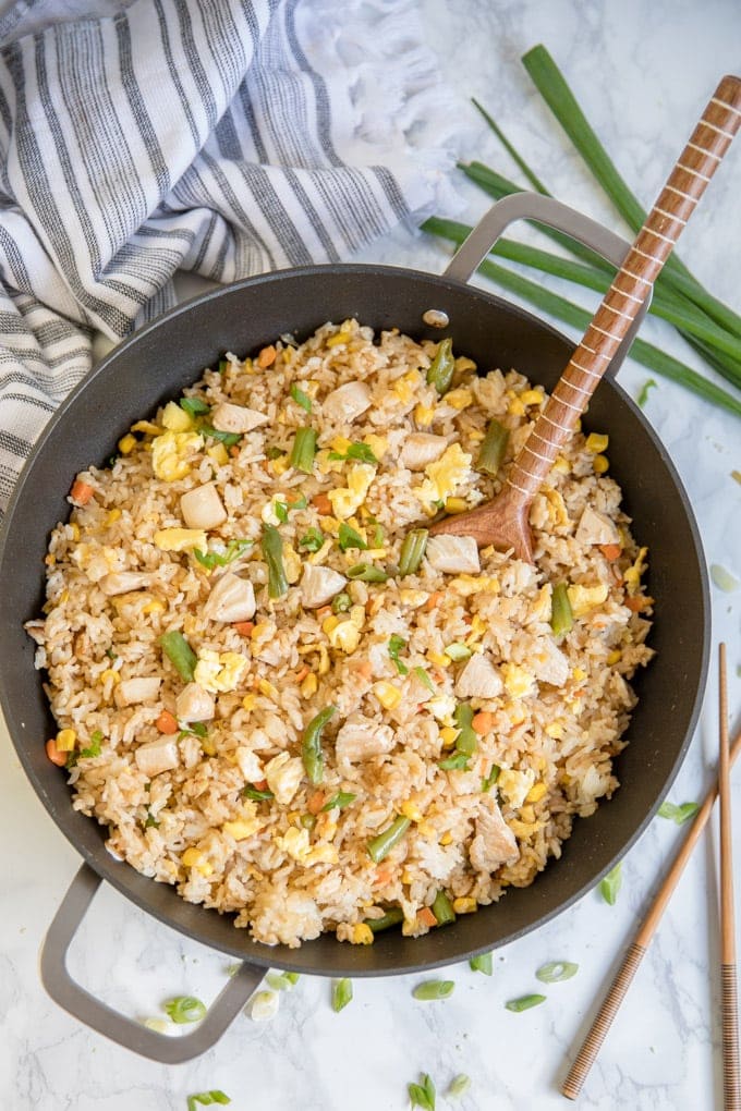 Chicken Fried Rice in a skillet with a long wooden spoon
