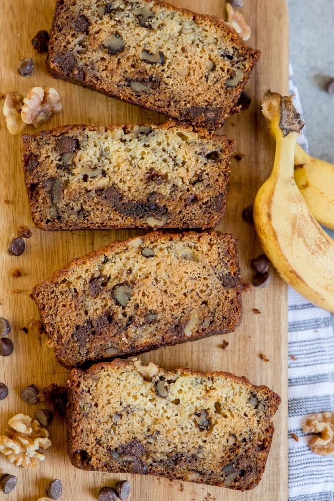 An overhead shot of four slices of chunky monkey banana bread on a cutting board.