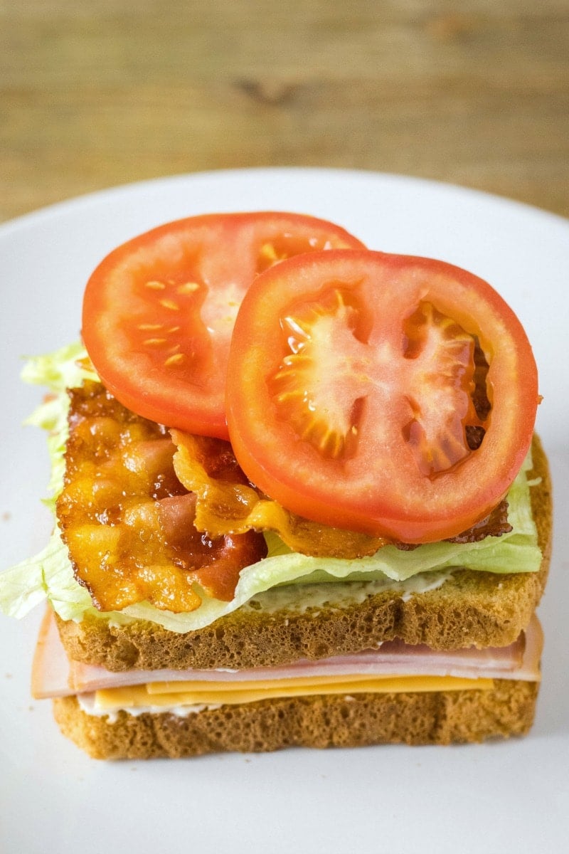 club sandwich ingredients layered on bread with mayo