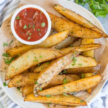 A plate of Potato Wedges and dish of ketchup