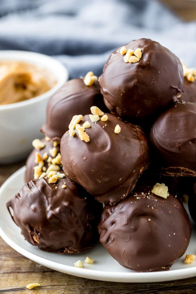 A plate of peanut butter balls dipped in chocolate and topped with chopped peanuts. 