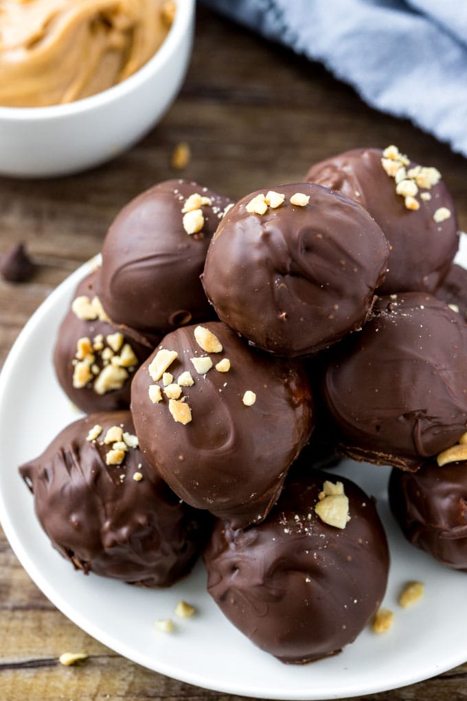 A plate of creamy peanut butter balls made with rice krispies and stacked in a pyramid. 