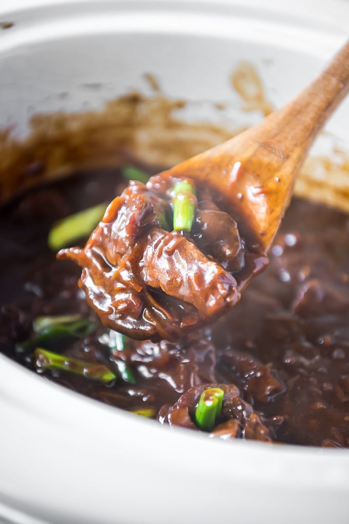 When you're in the mood for a delicious homemade version of your favorite Chinese takeout, this Slow Cooker Mongolian Beef is the answer! Slow Cooker Mongolian Beef on a wooden spoon.