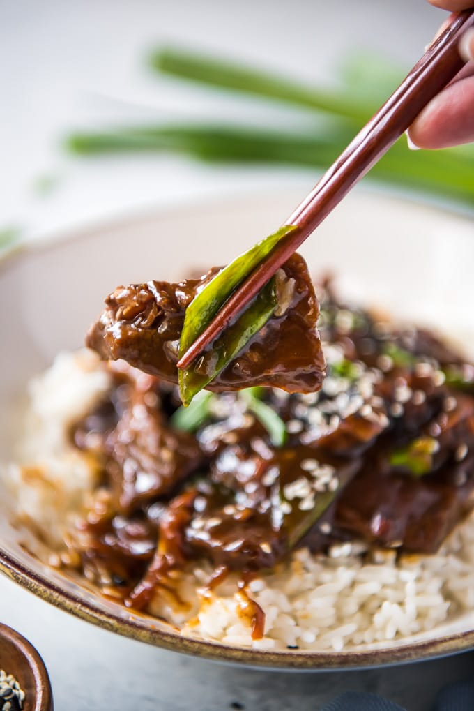 When you're in the mood for a delicious homemade version of your favorite Chinese takeout, this Slow Cooker Mongolian Beef is the answer! Slow Cooker Mongolian Beef held up with chopsticks