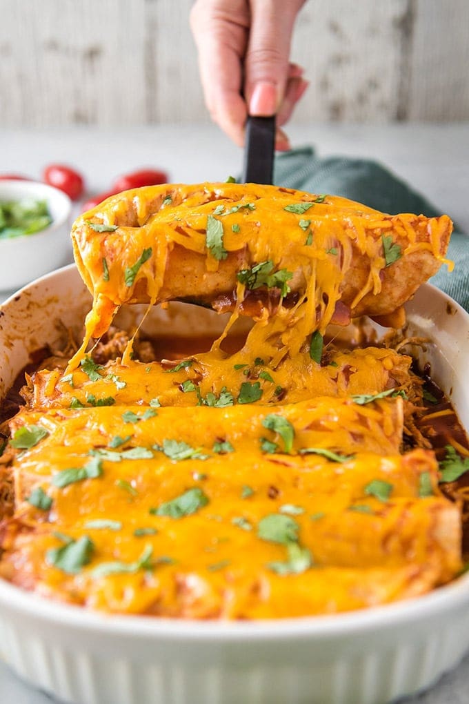 Chicken Enchiladas being lifted out of the pan with a spatula