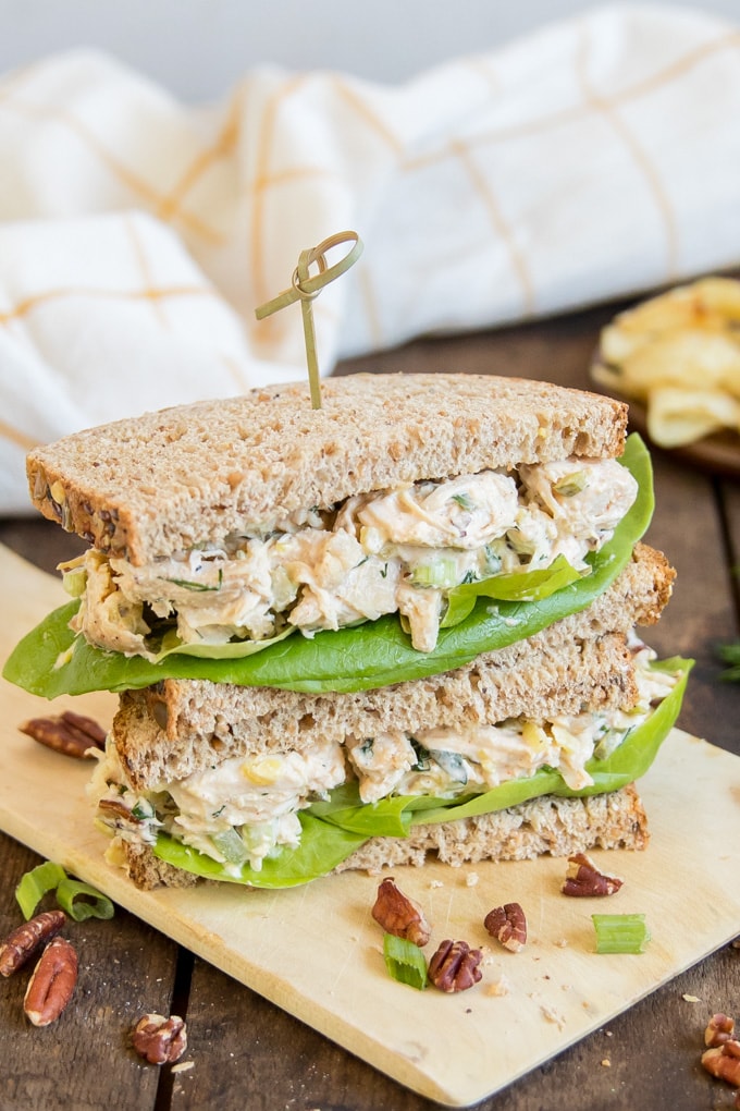 Two halves of a chicken salad sandwich stacked with a toothpick inserted in the top