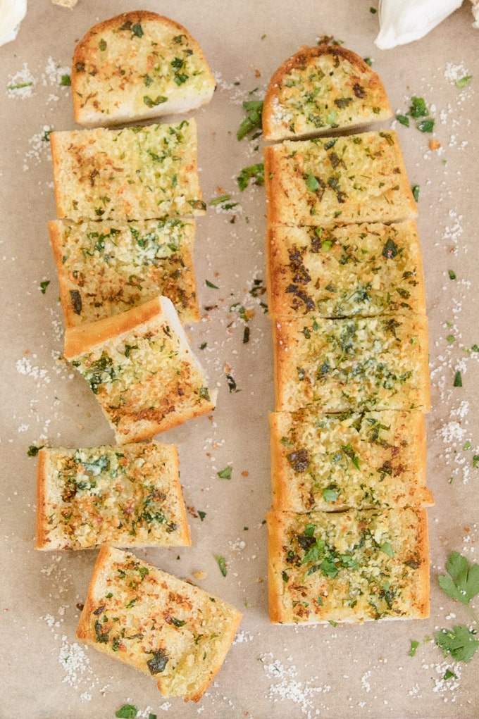 Round out any meal with this homemade Garlic Bread recipe, with homemade garlic butter and Parmesan cheese. This is how to make garlic bread the easy way. An overhead image with 2 sliced loaves of garlic bread.