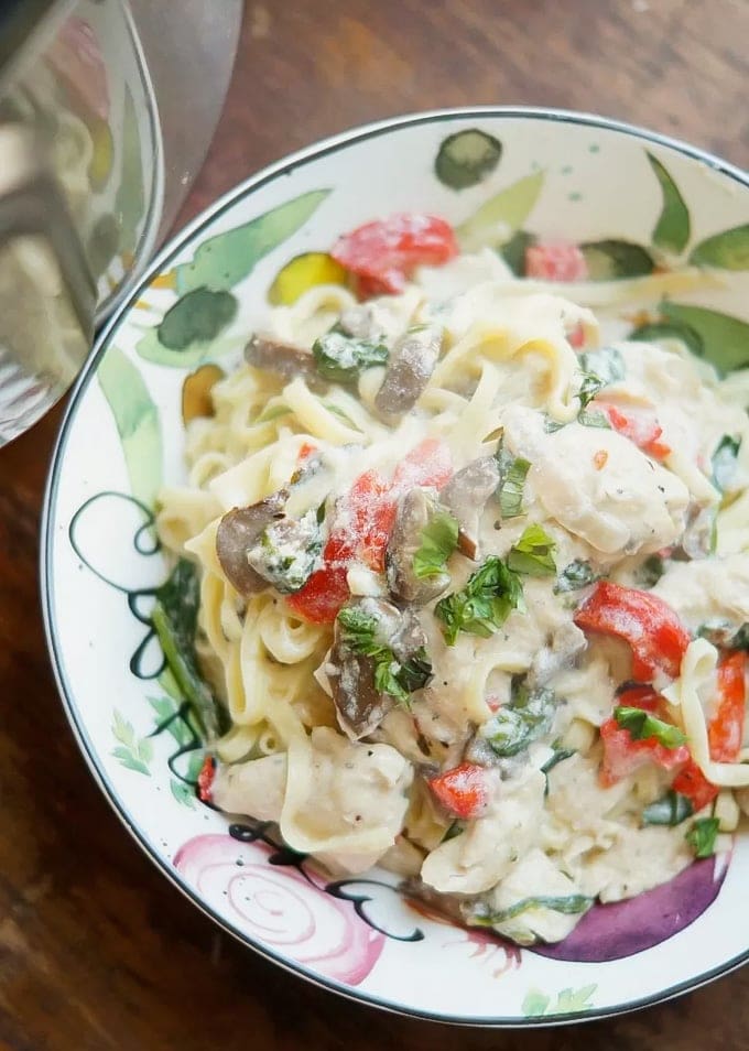 Chicken Florentine served over pasta in a serving bowl