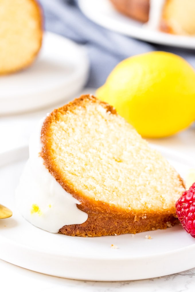 A slice of glazed lemon pound cake on it's side on a white plate. 