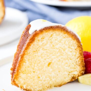 A slice of lemon pound cake with lemon glaze on a white plate.